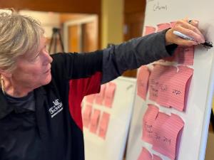 Linda makes notes on whiteboard next to sticky notes